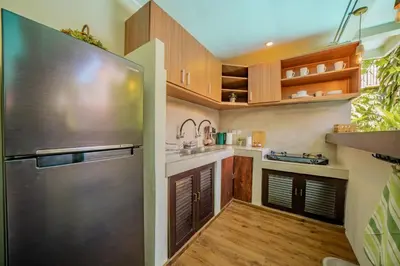 a kitchen with wooden cabinets and a stainless steel refrigerator at Villa Kiwi Seminyak in Seminyak