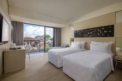 a hotel room with two beds and a balcony at Anathera Resort Kuta Bali Airport in Kuta