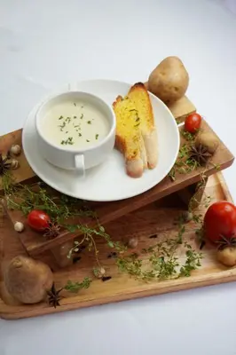 a plate with a bowl of soup and bread on a board at Anathera Resort Kuta Bali Airport in Kuta