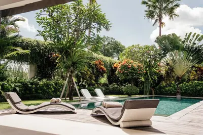 a pool with lounge chairs next to a swimming pool at Seminyak villa 3 chambres service 5 in Seminyak
