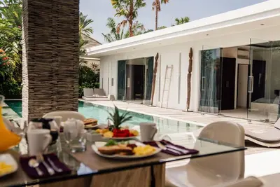 a table with a plate of food next to a swimming pool at Seminyak villa 3 chambres service 5 in Seminyak