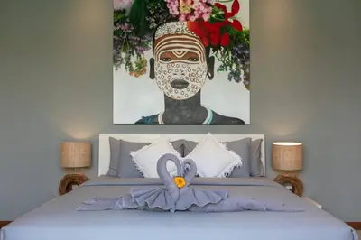 a bedroom with a bed with a painting on the wall at Amazing 4 BR villa with garden, pool in Seminyak in Seminyak