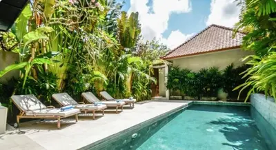 a pool with lounge chairs next to a house at 4BR Group Holiday, Walk to Fitness, Food, Beach in Seminyak