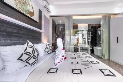 a bedroom with a white bed with black and white pillows at Villa Rama by JB Villas in Seminyak