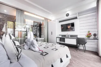 a bedroom with a large white bed with a desk at Villa Rama by JB Villas in Seminyak
