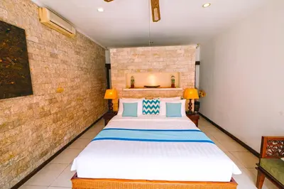 a bedroom with a bed and a brick wall at Villa Leona Seminyak in Seminyak