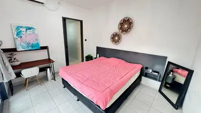a bedroom with a bed with a pink comforter and a desk at Ulun Kubu Villa in Kerobokan