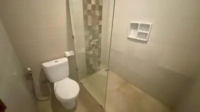 a bathroom with a toilet and a glass shower stall at Semilang House in Ngurah Rai International Airport