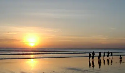 a group of people standing on the beach at sunset at Cozy room Kuta - 1 minutes to the beach by Micky Studio in Legian