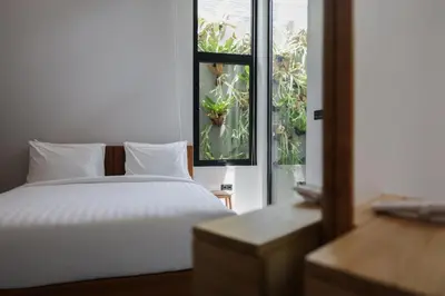 a bedroom with a white bed and a window at Rumah Christa in Seminyak