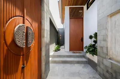 a hallway of a house with a wooden door at Rumah Christa in Seminyak