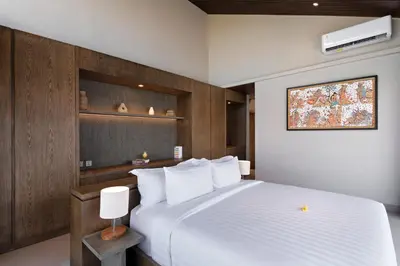 a bedroom with a large white bed and wooden walls at D'Padi Villa Canggu in Canggu
