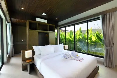 a bedroom with a large white bed and large windows at D'Padi Villa Canggu in Canggu
