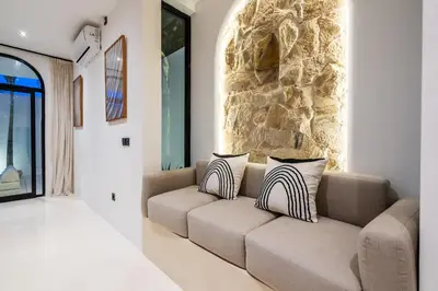 a living room with a couch and a stone wall at Casa Nalani in Kerobokan