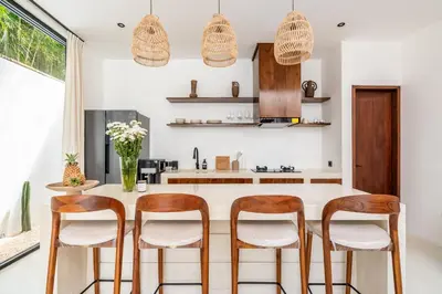 a kitchen with white countertops and wooden stools at Casa Nalani in Kerobokan