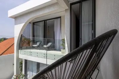 a balcony with glass doors and chairs on it at Brand New Luxury 5 Stars Designer Villa by Amare Villas in Kerobokan