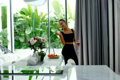 a woman in a black dress drinking from a wine glass at Brand New Luxury 5 Stars Designer Villa by Amare Villas in Kerobokan