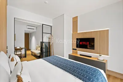 a bedroom with a bed and a tv on a wall at Calira by Kozystay - Nusa Dua in Nusa Dua