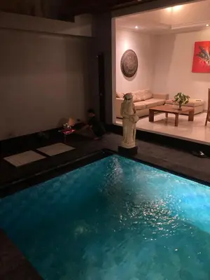 a man sitting in a room with a swimming pool at Ben & B villa in Kerobokan