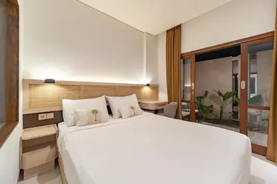 a bedroom with a large white bed and a desk at The Hita Uluwatu in Jimbaran