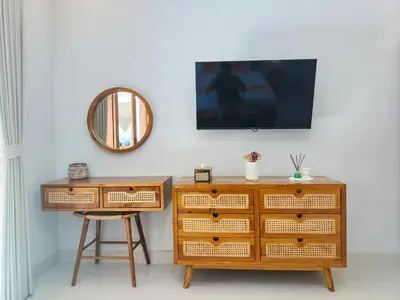 a wooden dresser and a stool next to a mirror at Rumah Kodel4 by iBali Management in Seminyak