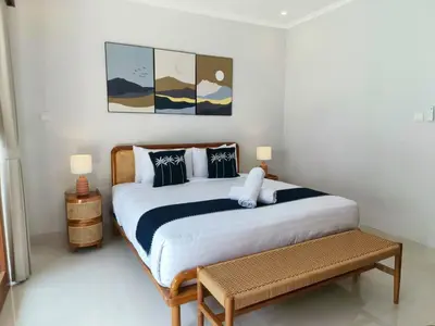 a bedroom with a large bed and a bench at Rumah Kodel4 by iBali Management in Seminyak