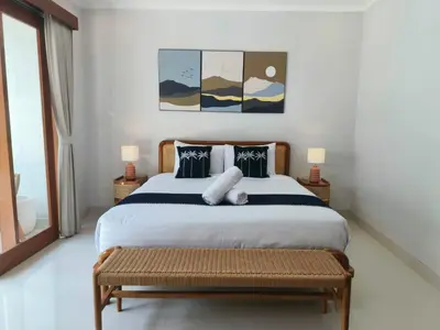 a bedroom with a large bed and a bench at Rumah Kodel4 by iBali Management in Seminyak
