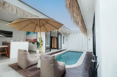 an indoor pool with an umbrella in a house at Queen Villa D1 by Betterplace in Seminyak