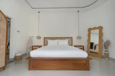 a bedroom with a white bed and a mirror at Queen Villa D1 by Betterplace in Seminyak