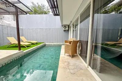a swimming pool with chairs next to a house at Garden Leaf Villa - 2 Bedroom Pool Villa with Minimum Stay 2 Nights in Nusa Dua