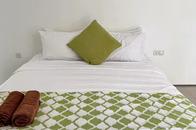 a bed with a green pillow and two towels on it at Garden Leaf Villa - 2 Bedroom Pool Villa with Minimum Stay 2 Nights in Nusa Dua