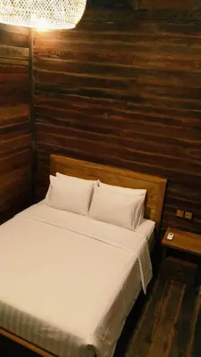 a bed with white sheets and pillows in a room at Queen's Cabin in Kerobokan