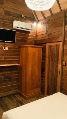 a room with wooden walls and a tv and a bed at Queen's Cabin in Kerobokan