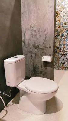 a white toilet in a bathroom with a wall at Queen's Cabin in Kerobokan