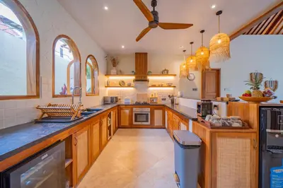 a large kitchen with wooden cabinets and a ceiling fan at Luxury Balinese Oasis with private pool - 2 BR in Kerobokan