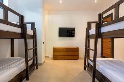 a room with three bunk beds and a tv at Walk, Best of Berawa, 5bd villa, 2min from Finns in Canggu