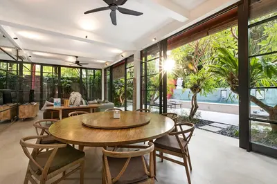 a dining room with tables and chairs and windows at Walk, Best of Berawa, 5bd villa, 2min from Finns in Canggu