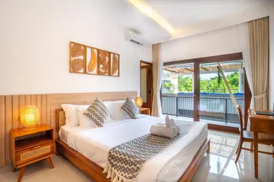 a bedroom with a bed and a balcony at Jimbaran Breeze Villa By Island Escape in Jimbaran