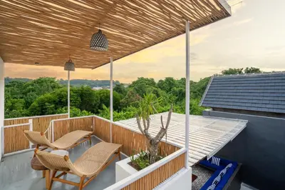 a patio with two chairs and a table on a roof at Jimbaran Breeze Villa By Island Escape in Jimbaran