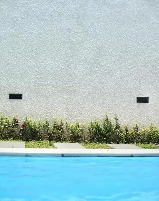 a wall with two black posts next to a swimming pool at The Cendana Villa Umalas in Badung