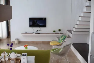 a living room with a couch and chairs and a tv at The Cendana Villa Umalas in Badung