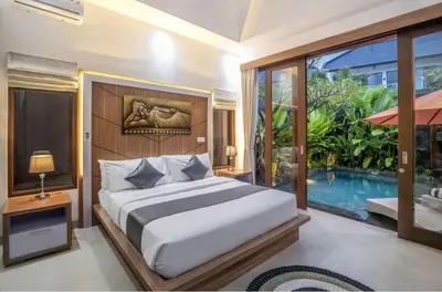a bedroom with a bed and a swimming pool at Puri Sahadewa Seminyak in Seminyak