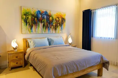 a bedroom with a bed with a painting on the wall at Peaceful 2br with pool & garden in Seminyak
