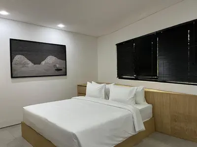 a bedroom with a white bed and two windows at Teras by Tamora in Badung