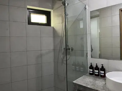 a bathroom with a glass shower with a sink and a mirror at Teras by Tamora in Badung
