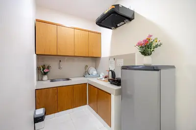 a small kitchen with wooden cabinets and a refrigerator at Bali True Living in Denpasar