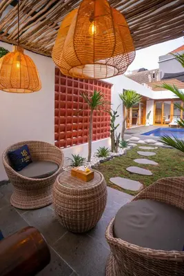 a patio with wicker chairs and tables and lights at Zahra Villas in Nusa Dua