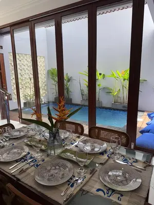 a wooden table with plates and glasses on top of it at Modern 3BR Villa with Private Pool & Rooftop in Nusa Dua in Nusa Dua