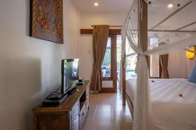 a bedroom with a canopy bed and a television in it at Genta- Petitenget 2BR villa, walk to beach! in Seminyak