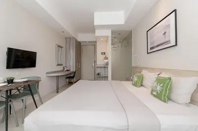 a bedroom with a large white bed and a desk at Bali Bustle Kuta Coliving & Coworking Space in Legian